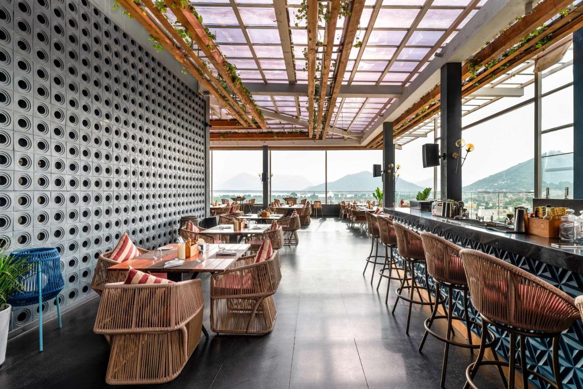 a restaurant with tables and chairs with mountains in the background at Parallel Hotel Udaipur, a member of Radisson Individuals in Udaipur