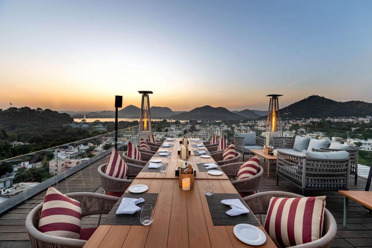 a long table on a rooftop with a view of the city at Parallel Hotel Udaipur, a member of Radisson Individuals in Udaipur