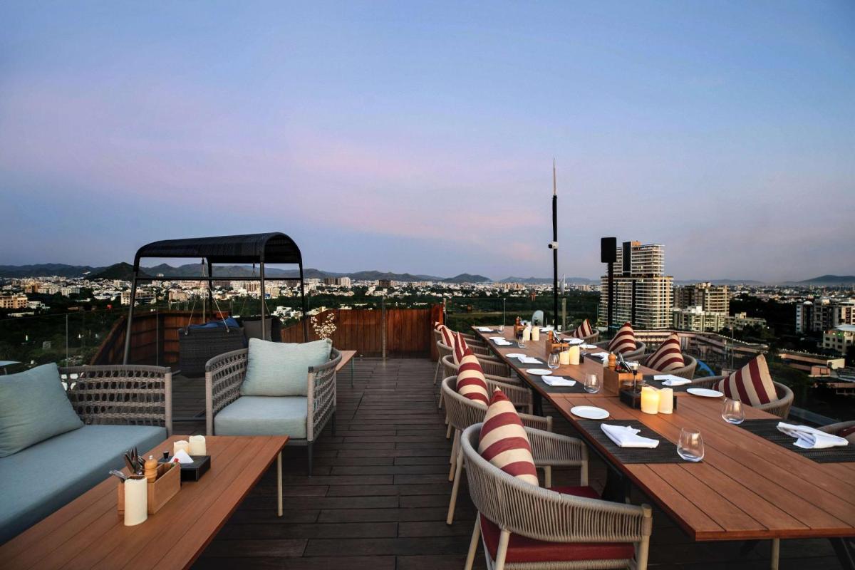 a restaurant with tables and chairs on a roof at Parallel Hotel Udaipur, a member of Radisson Individuals in Udaipur