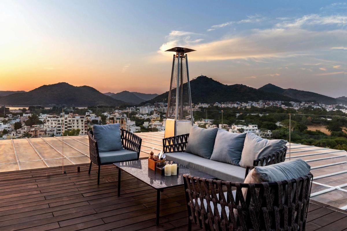 a patio with a couch and chairs on a deck at Parallel Hotel Udaipur, a member of Radisson Individuals in Udaipur