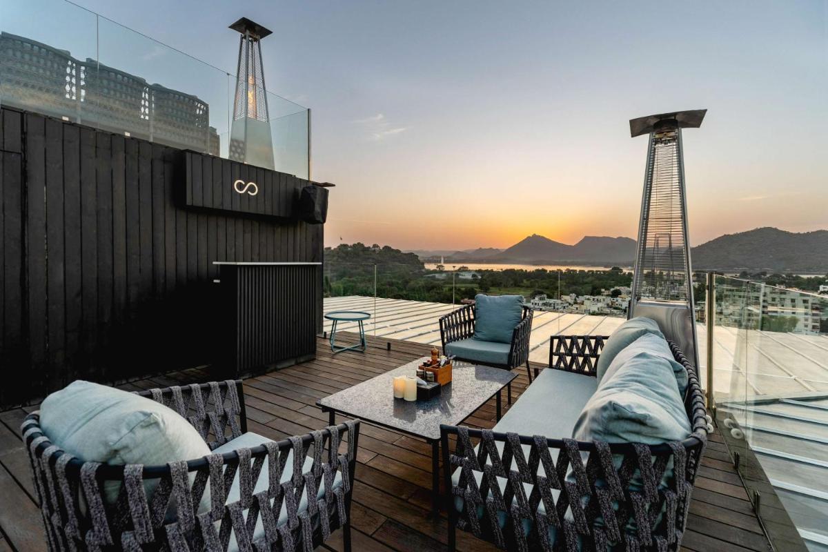 a rooftop deck with chairs and a couch on a building at Parallel Hotel Udaipur, a member of Radisson Individuals in Udaipur