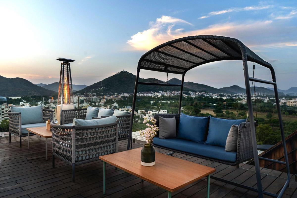 a patio with a blue couch on a roof at Parallel Hotel Udaipur, a member of Radisson Individuals in Udaipur