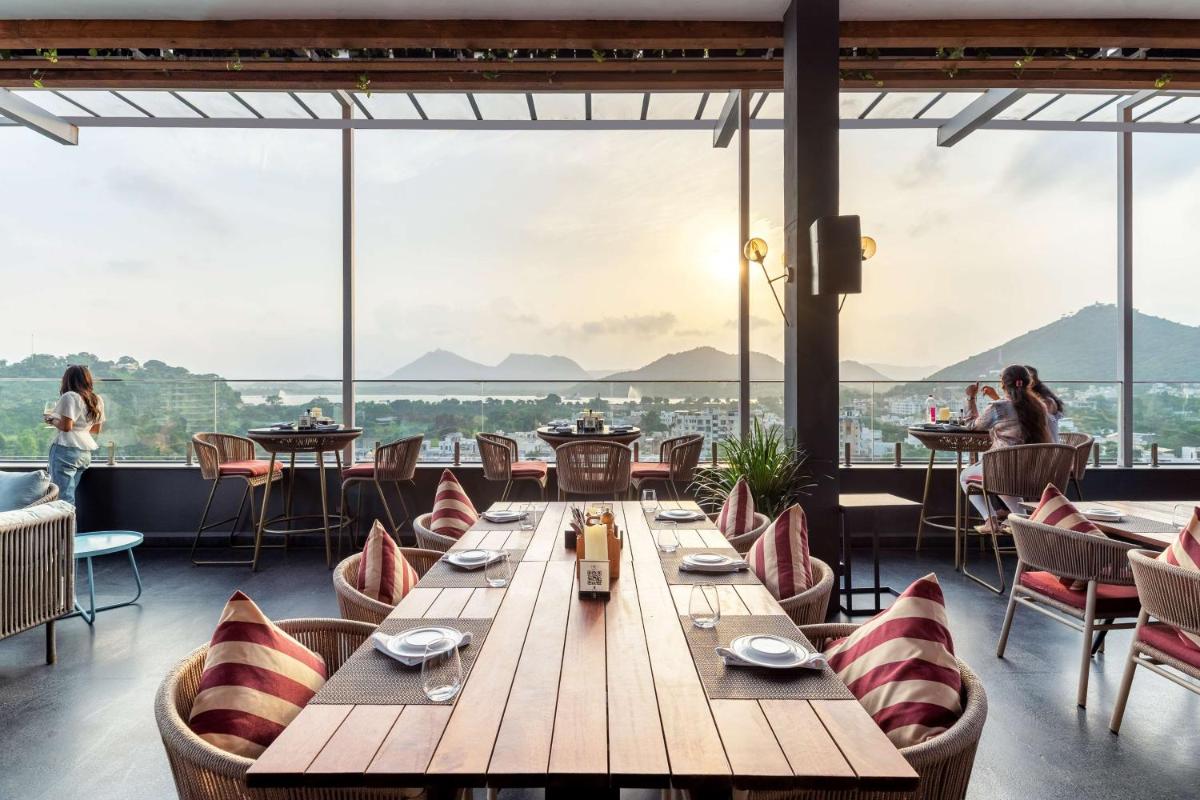 a dining room with tables and chairs and large windows at Parallel Hotel Udaipur, a member of Radisson Individuals in Udaipur