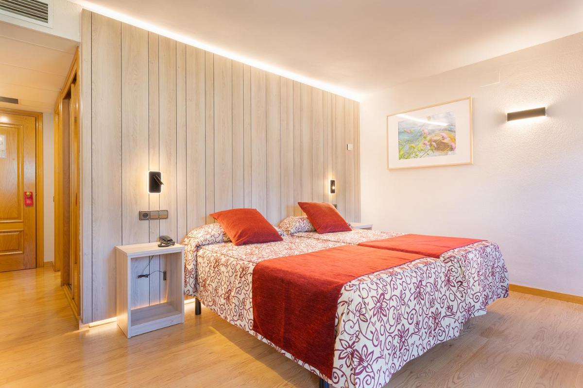 Una habitación de hotel con una cama con almohadas rojas. en Hotel Eth Solan & SPA, en Vielha