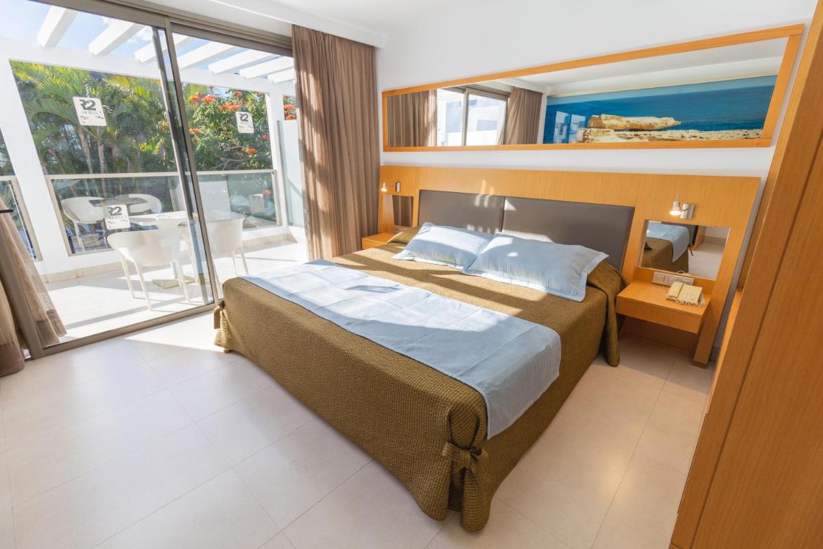 Un dormitorio con una cama grande y una ventana grande. en R2 Bahia Playa - Adults Only, en Tarajalejo