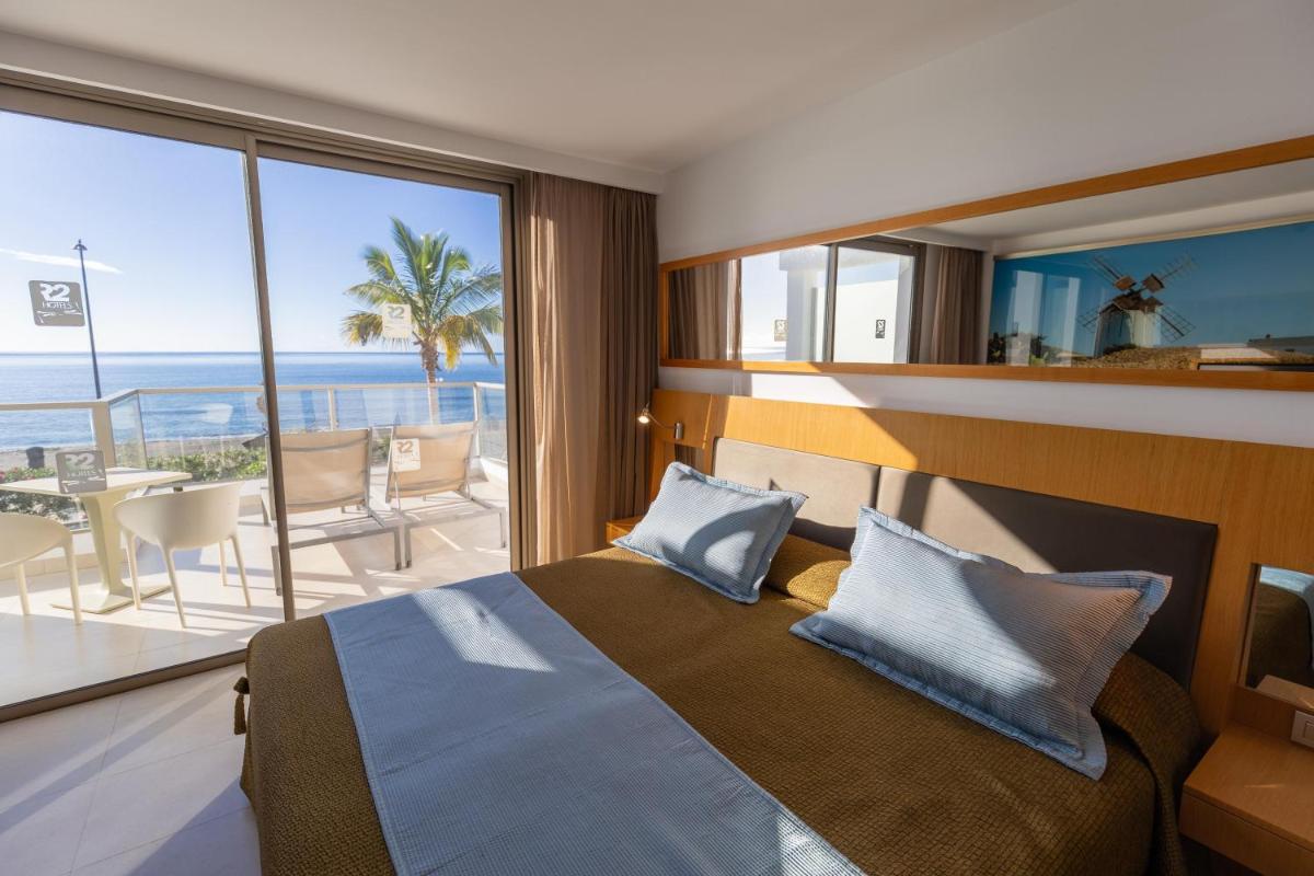Un dormitorio con una cama y vista al mar. en R2 Bahia Playa - Adults Only, en Tarajalejo