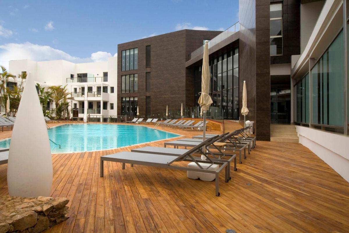 Una piscina con tumbonas en la terraza de un edificio. en R2 Bahia Playa - Adults Only, en Tarajalejo