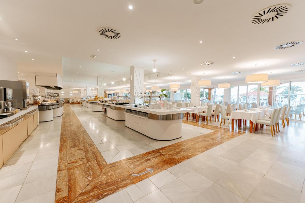 Una gran cocina con mesas y sillas en un restaurante. en R2 Buganvilla Hotel & Spa, en Morro del Jable