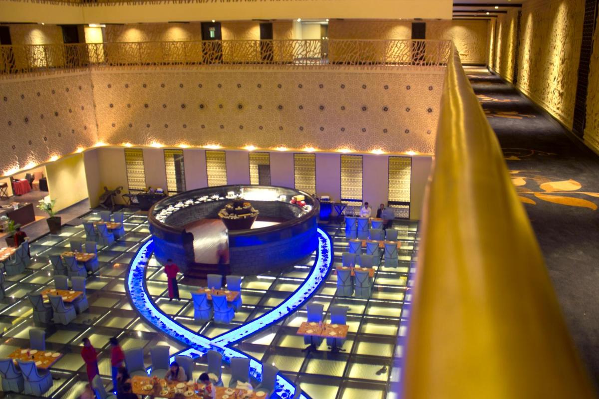 a large room with blue chairs and a stage at Sterlings Mac Hotel in Bengaluru