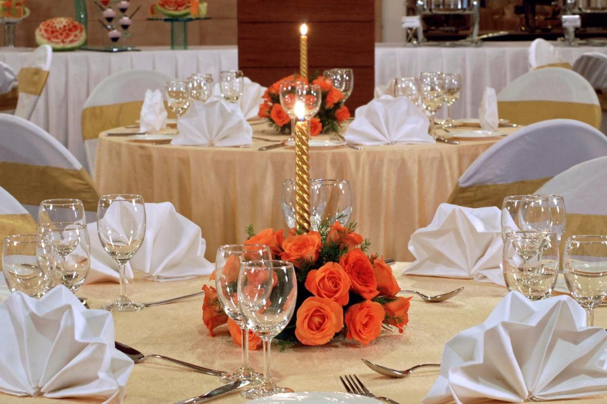 a table with orange flowers and wine glasses on it at Fortune JP Palace, Mysore - Member ITC Hotels' Group in Mysore