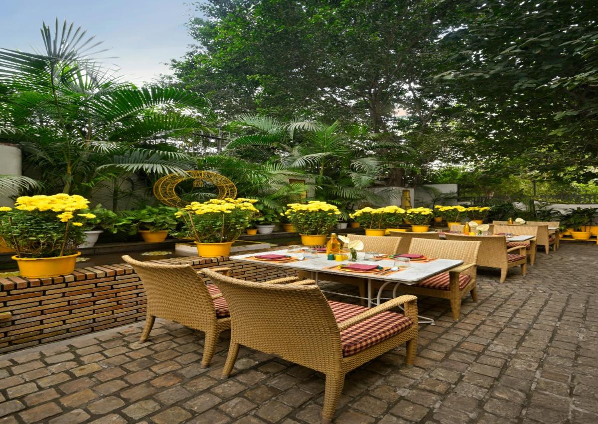 a patio with tables and chairs and yellow flowers at Ambassador, New Delhi - IHCL SeleQtions in New Delhi a patio with tables and chairs and yellow flowers at Ambassador, New Delhi - IHCL SeleQtions in New Delhi