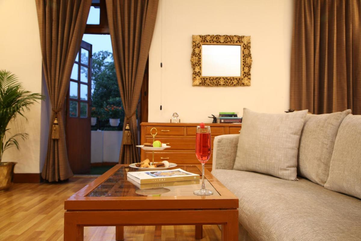a living room with a couch and a table with a wine glass at Ambassador, New Delhi - IHCL SeleQtions in New Delhi a living room with a couch and a table with a wine glass at Ambassador, New Delhi - IHCL SeleQtions in New Delhi