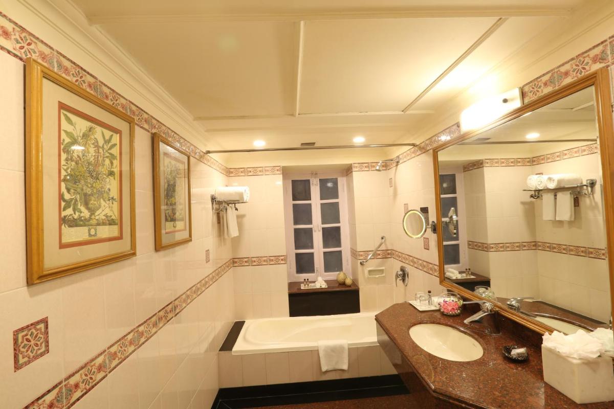 a bathroom with a tub and a sink and a mirror at Ambassador, New Delhi - IHCL SeleQtions in New Delhi a bathroom with a tub and a sink and a mirror at Ambassador, New Delhi - IHCL SeleQtions in New Delhi