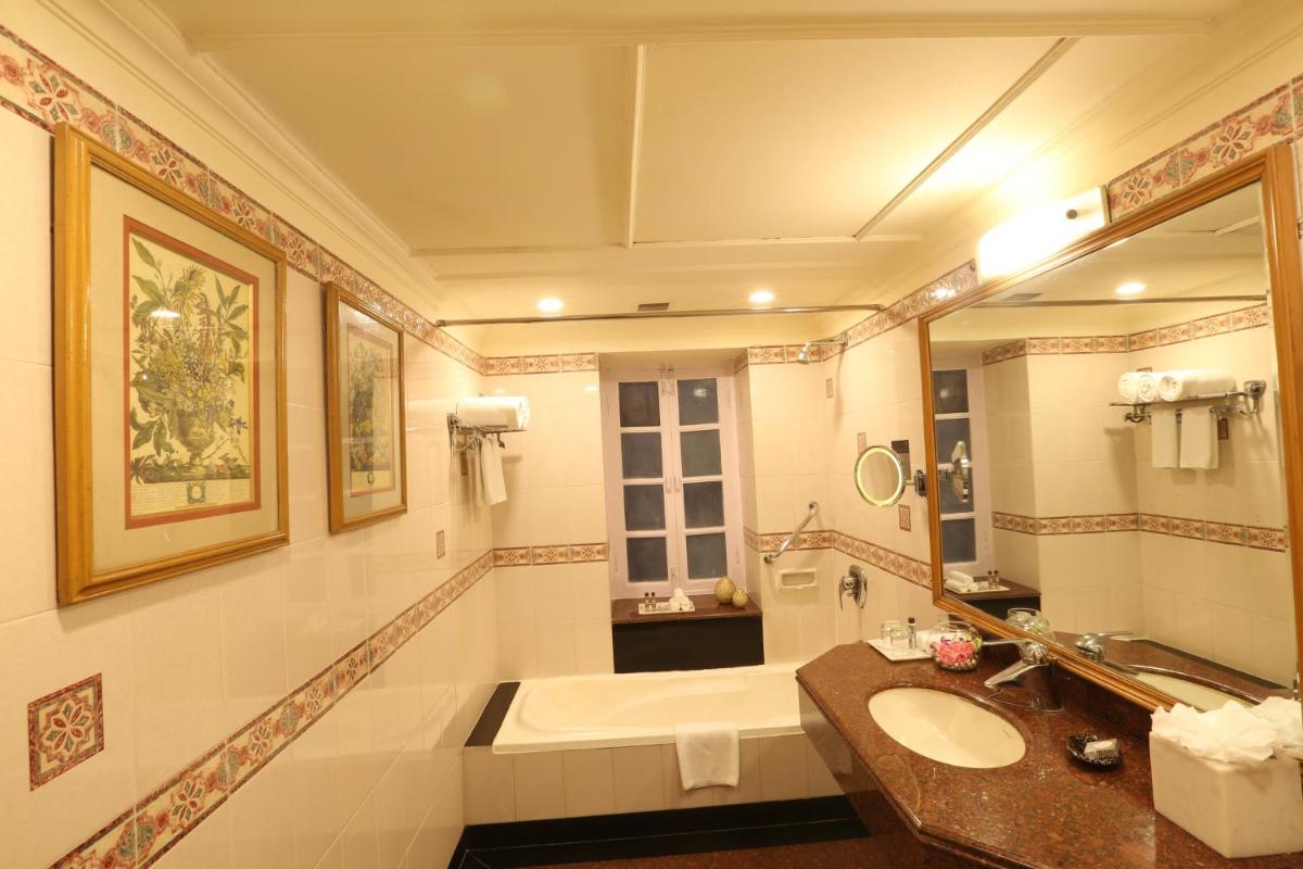 a bathroom with a sink and a tub and a mirror at Ambassador, New Delhi - IHCL SeleQtions in New Delhi a bathroom with a sink and a tub and a mirror at Ambassador, New Delhi - IHCL SeleQtions in New Delhi