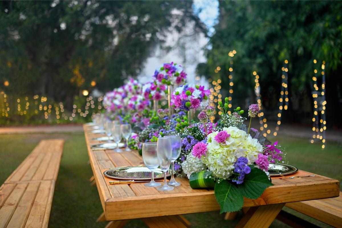 a wooden table with wine glasses and flowers on it at Ambassador, New Delhi - IHCL SeleQtions in New Delhi a wooden table with wine glasses and flowers on it at Ambassador, New Delhi - IHCL SeleQtions in New Delhi