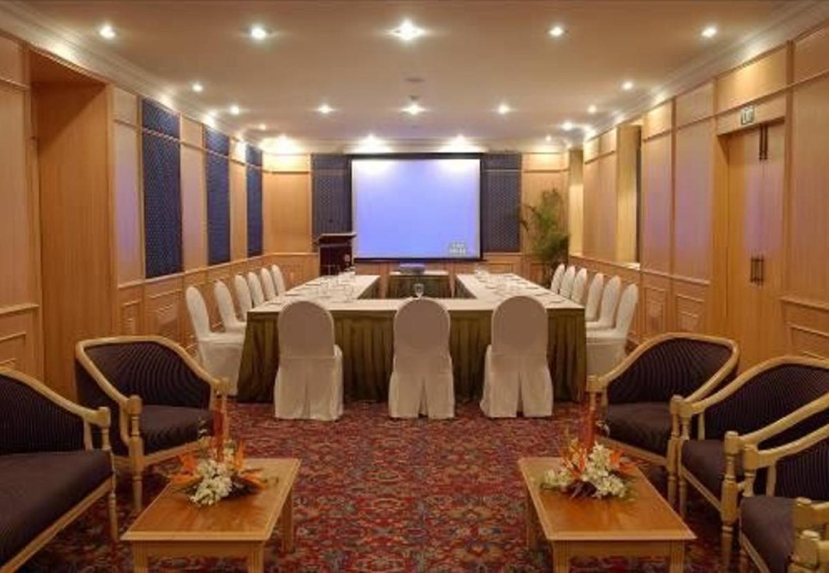 a conference room with a large table with chairs and a screen at Ambassador, New Delhi - IHCL SeleQtions in New Delhi a conference room with a large table with chairs and a screen at Ambassador, New Delhi - IHCL SeleQtions in New Delhi