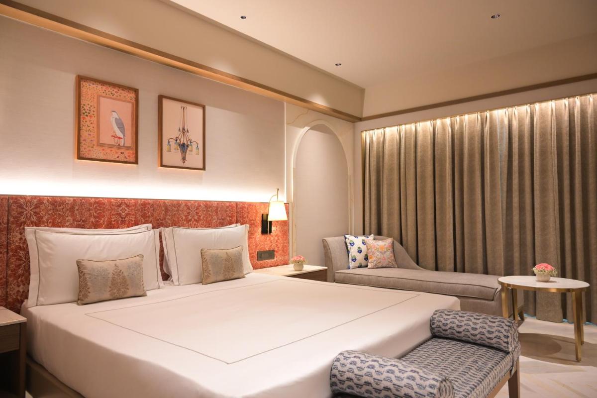 a hotel room with a large bed and a chair at Taj Agra in Agra