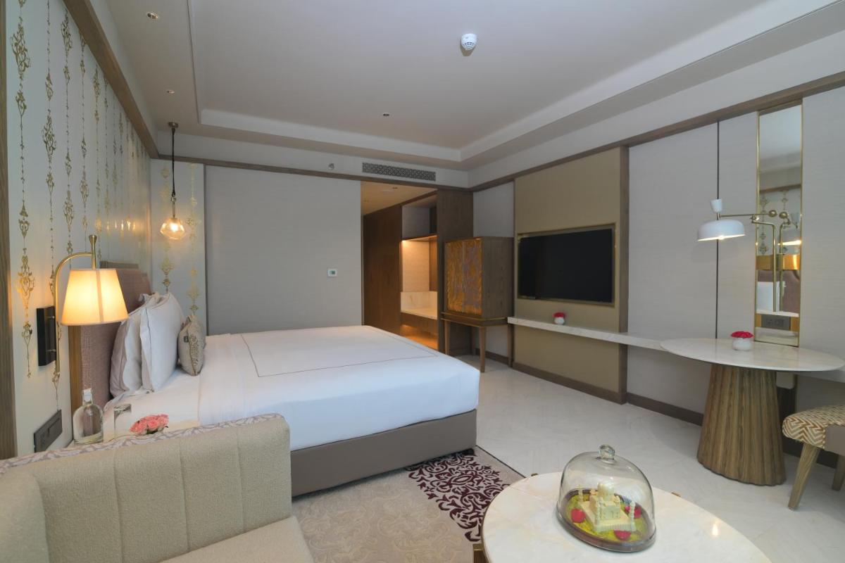 a bedroom with a large bed and a living room at Taj Agra in Agra