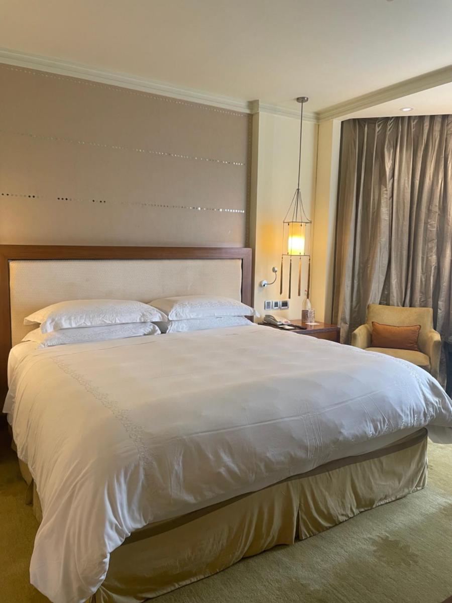 a bedroom with a large white bed and a chair at ITC Maurya, a Luxury Collection Hotel, New Delhi in New Delhi a bedroom with a large white bed and a chair at ITC Maurya, a Luxury Collection Hotel, New Delhi in New Delhi