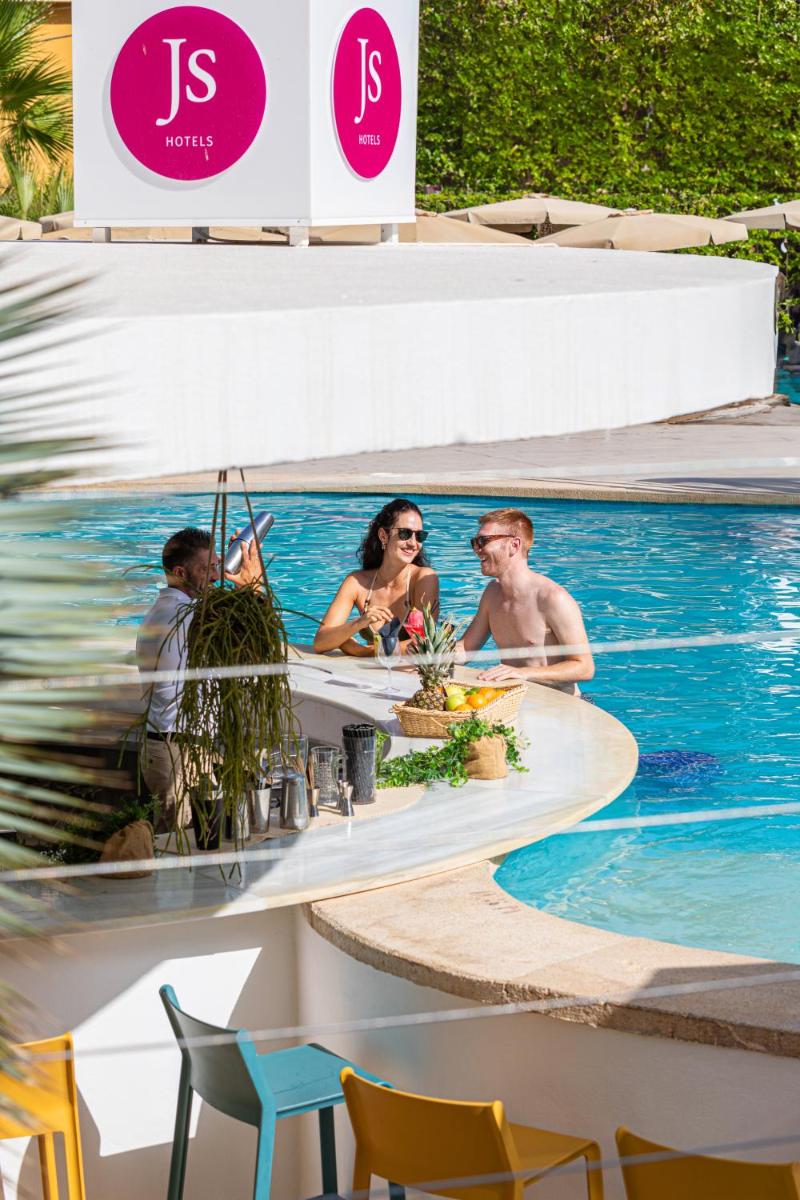un grupo de personas sentadas alrededor de una piscina en un complejo en JS Palma Stay - Adults Only, en Can Pastilla