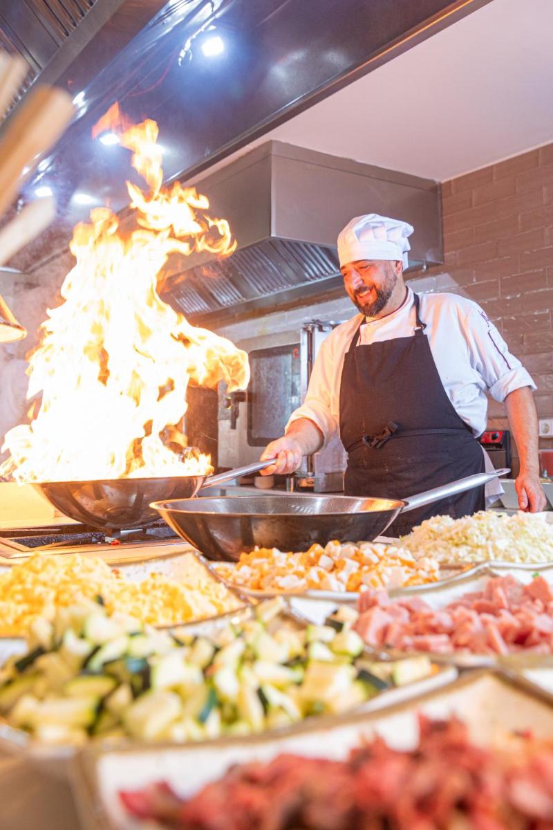 Un chef preparando comida en la cocina de un restaurante. en JS Sol de Alcudia, en Puerto de Alcudia