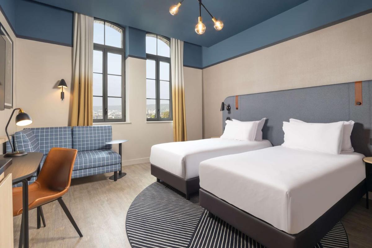 une chambre d'hôtel avec deux lits et une chaise dans l'établissement Hyatt Place Rouen, à Rouen