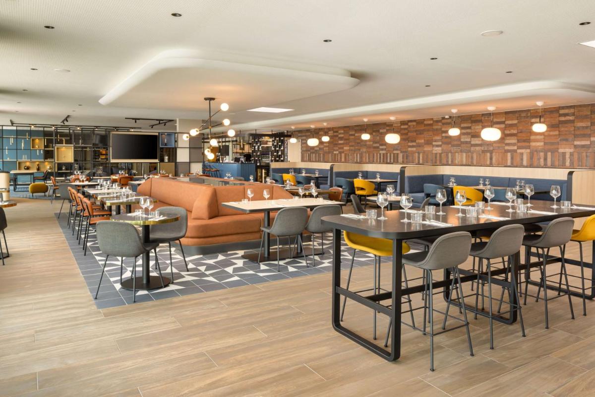 un restaurant avec des tables, des chaises et un canapé dans l'établissement Hyatt Place Rouen, à Rouen