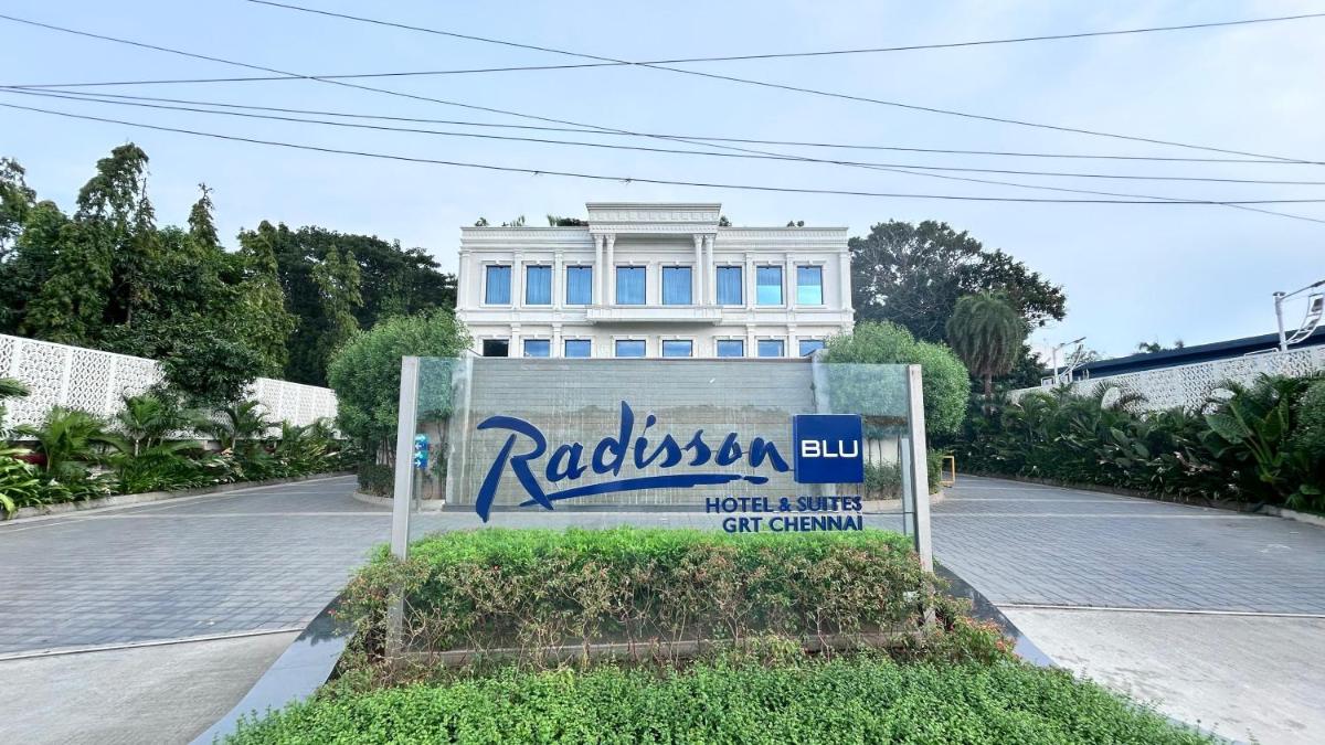 a sign in front of a white building at Radisson Blu Hotel & Suites GRT Chennai in Chennai