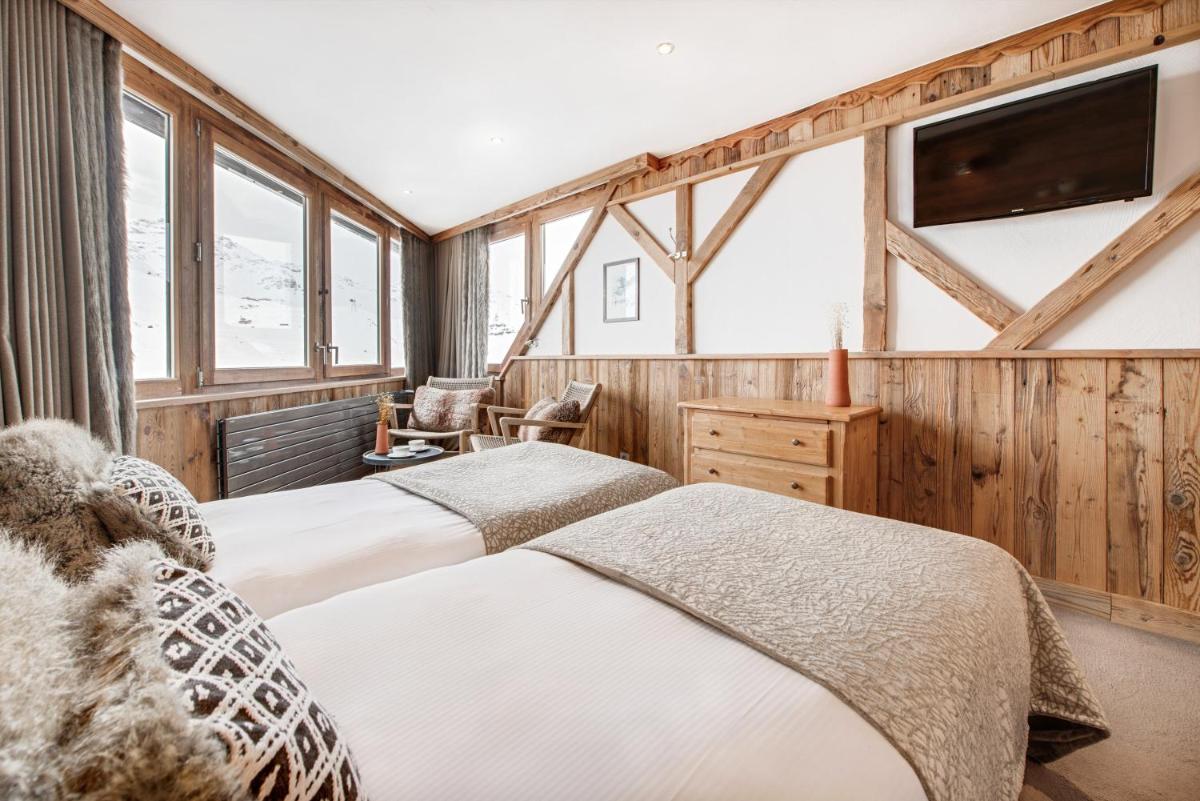 - 2 lits dans une chambre dotée de murs en bois et de fenêtres dans l'établissement Hotel 3 Vallées Val Thorens, à Val Thorens