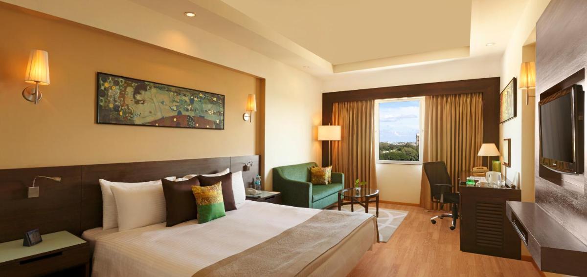 a hotel room with a bed and a desk at Lemon Tree Premier, Ulsoor Lake, Bengaluru in Bengaluru