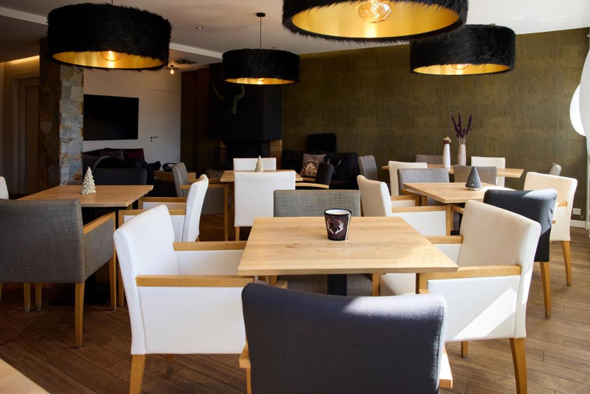 un restaurant avec des tables en bois et des chaises blanches dans l'établissement Hôtel Le Grand Tétras, à Font-Romeu
