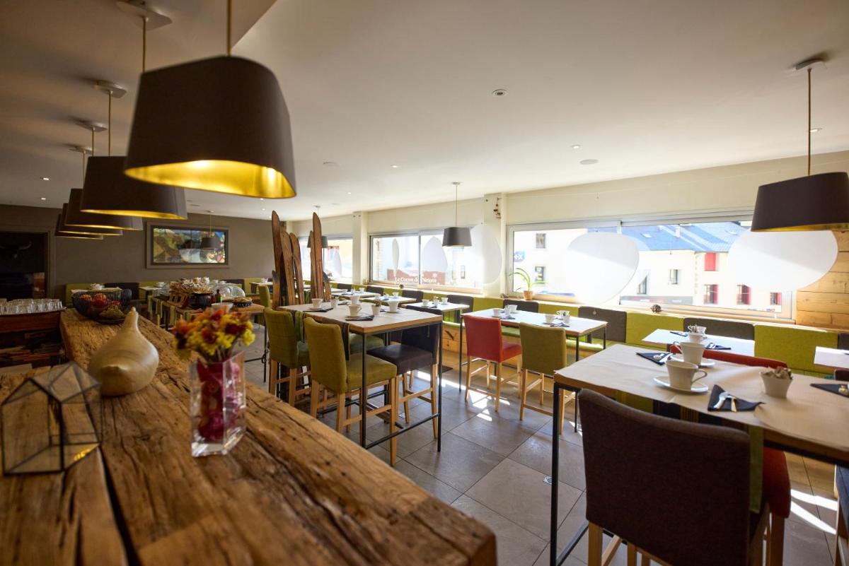 un restaurant avec une grande table et des chaises en bois dans l'établissement Hôtel Le Grand Tétras, à Font-Romeu