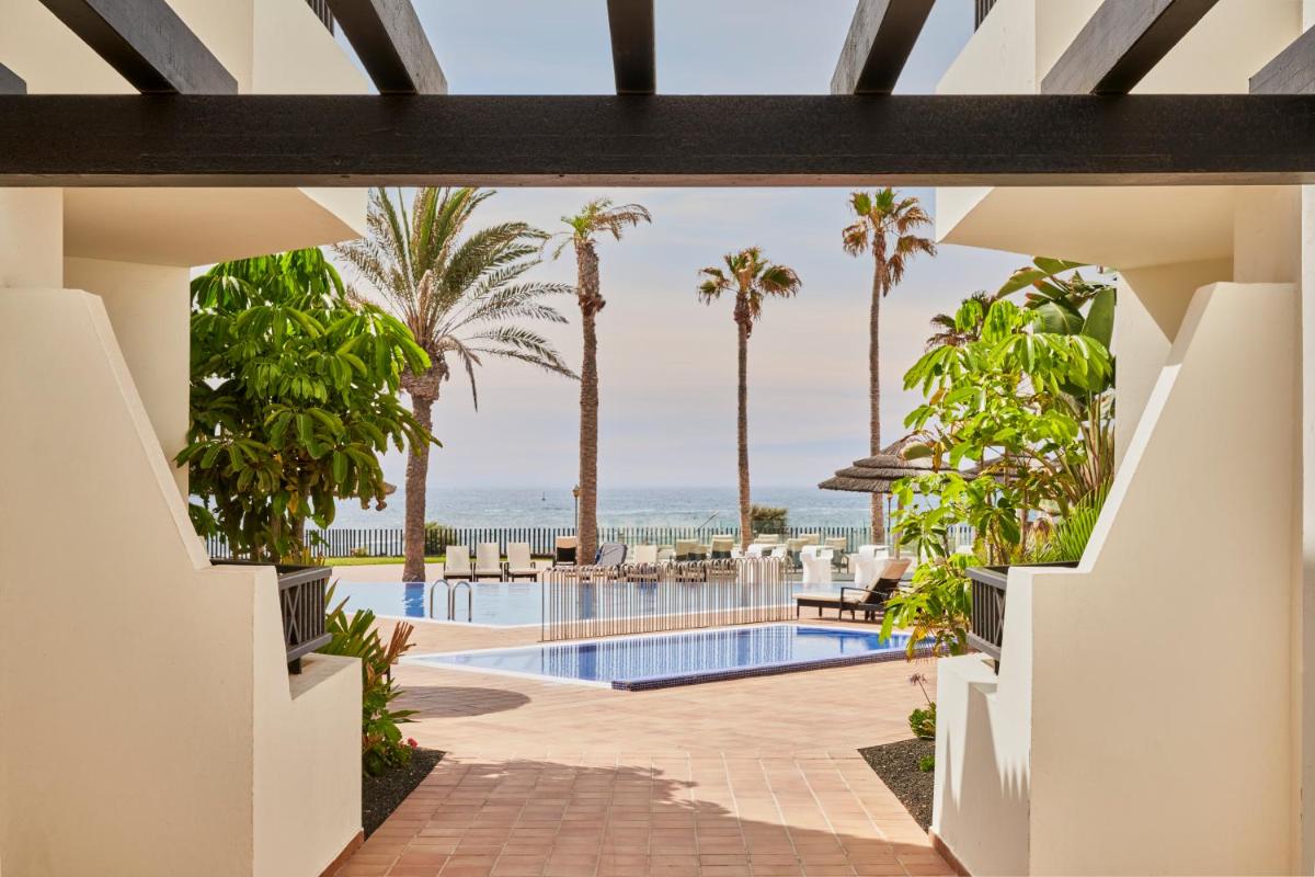 Una vista de la piscina del resort con palmeras. en Barceló Fuerteventura Royal Level, en Caleta de Fuste