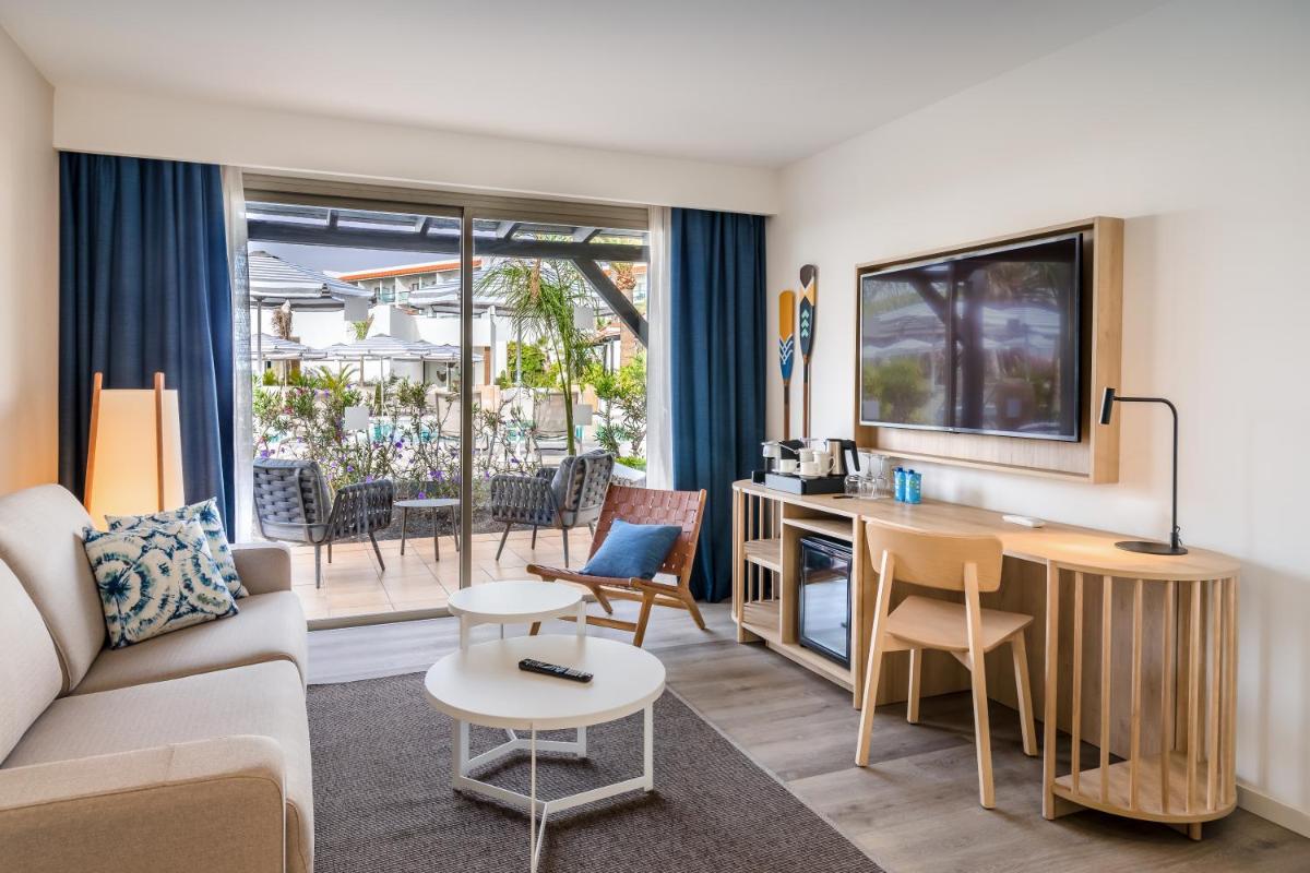 Una sala de estar con un sofá, una mesa y sillas. en Barceló Fuerteventura Royal Level - Adults Only, en Caleta de Fuste