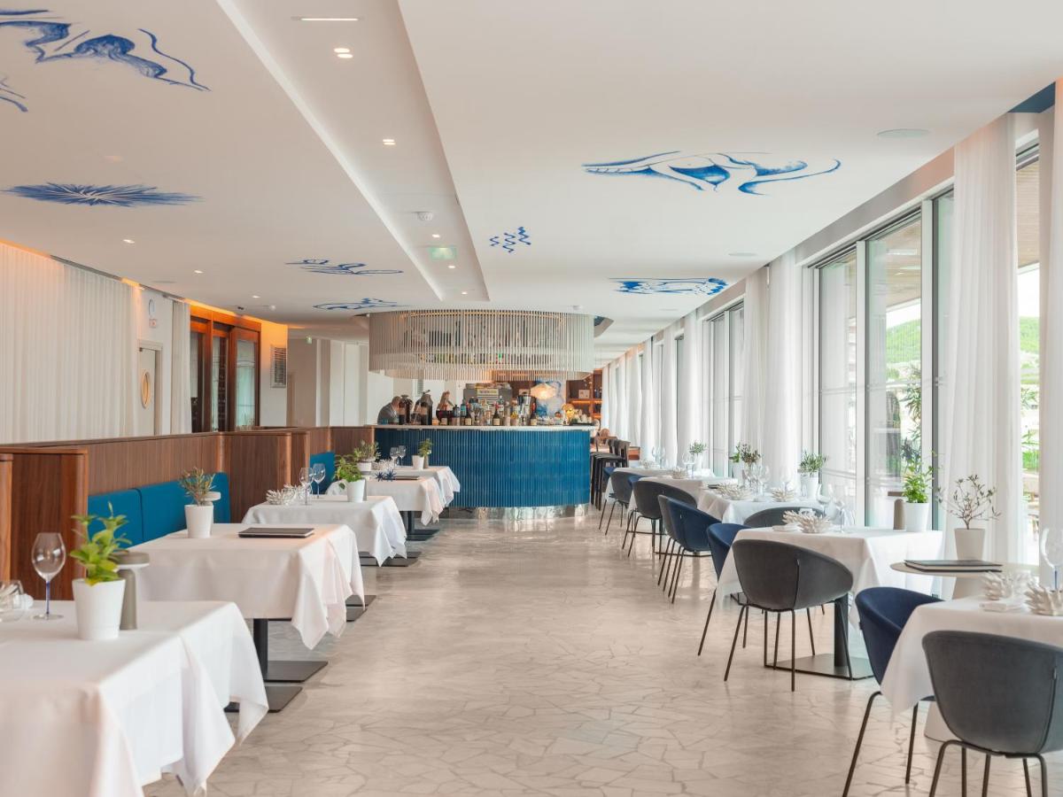 un restaurant avec des tables et des chaises blanches et des fenêtres dans l'établissement Bleu Hôtel & Spa, à Carry-le-Rouet