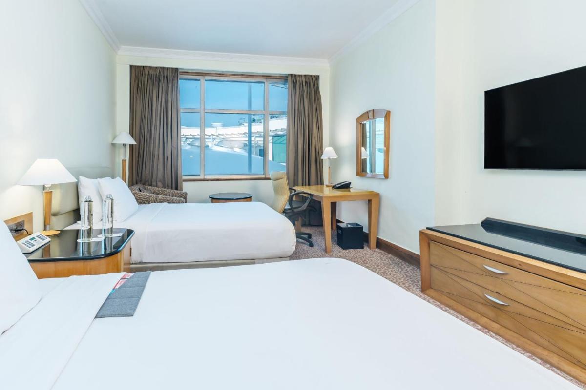 a hotel room with two beds and a flat screen tv at Le Royal Meridien Chennai in Chennai