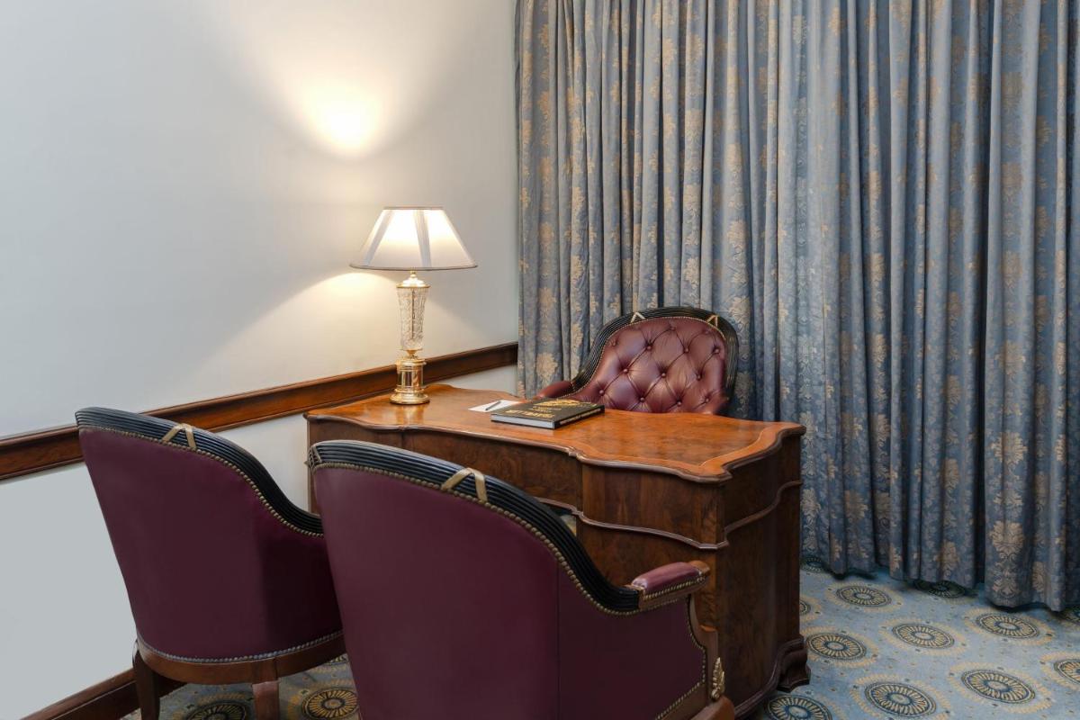 a room with a desk with a lamp and two chairs at Le Royal Meridien Chennai in Chennai