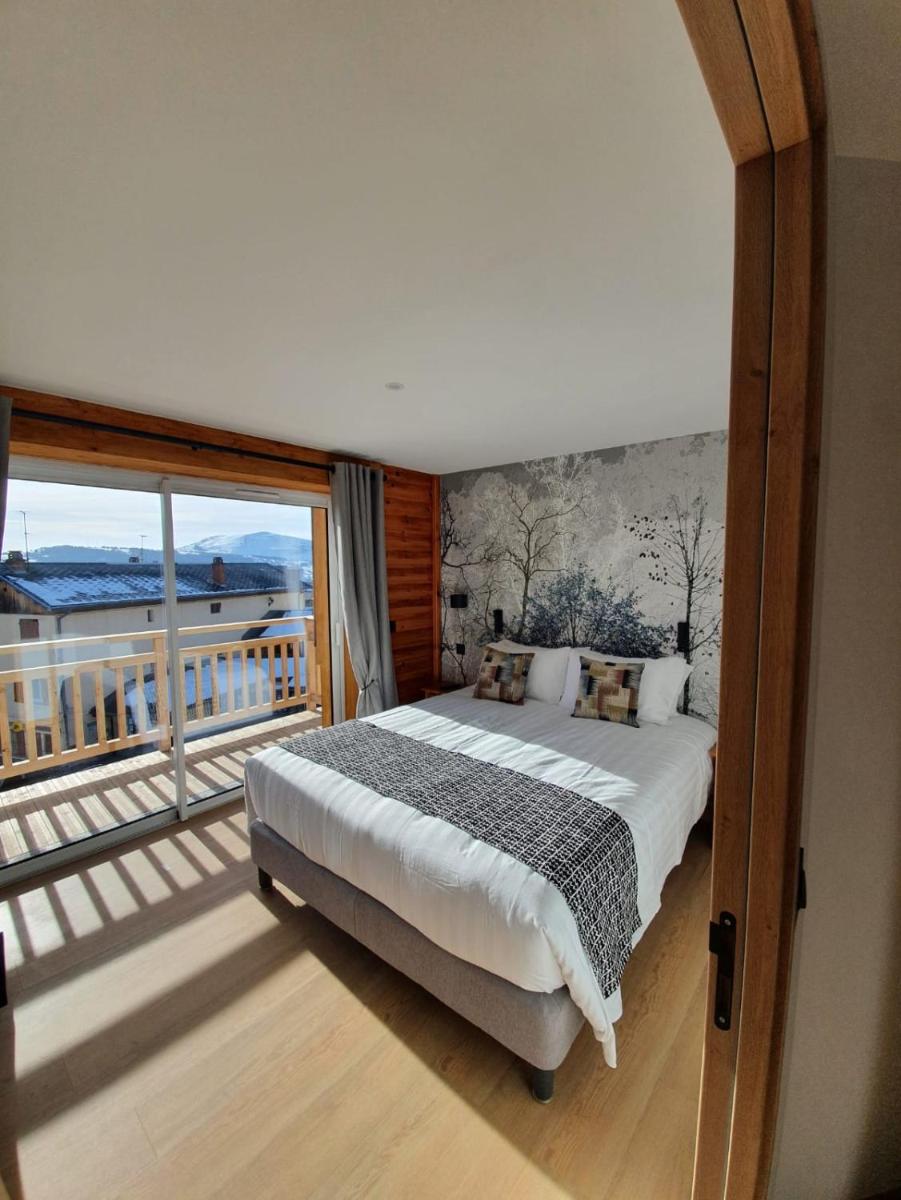 une chambre avec un grand lit et un balcon dans l'établissement Logis Hôtel Les Autanes & Spa, à Ancelle