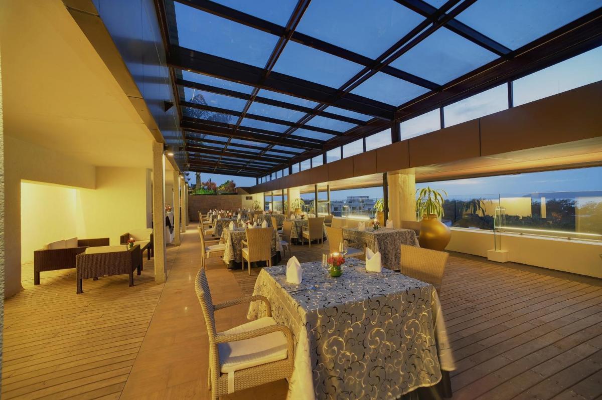 a restaurant with tables and chairs and a large glass ceiling at Vivanta Goa, Panaji in Panaji a restaurant with tables and chairs and a large glass ceiling at Vivanta Goa, Panaji in Panaji