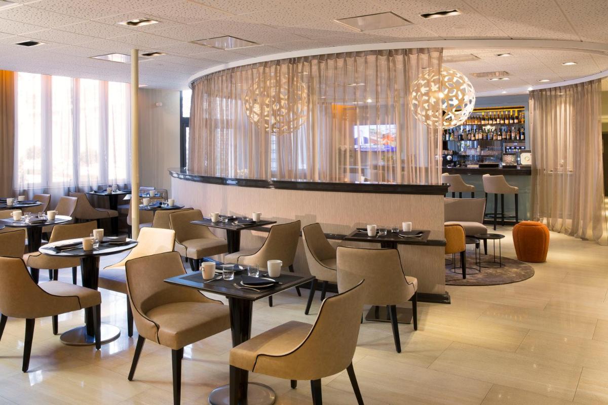 une salle à manger avec tables, chaises et lustres dans l'établissement Oceania Le Jura Dijon, à Dijon