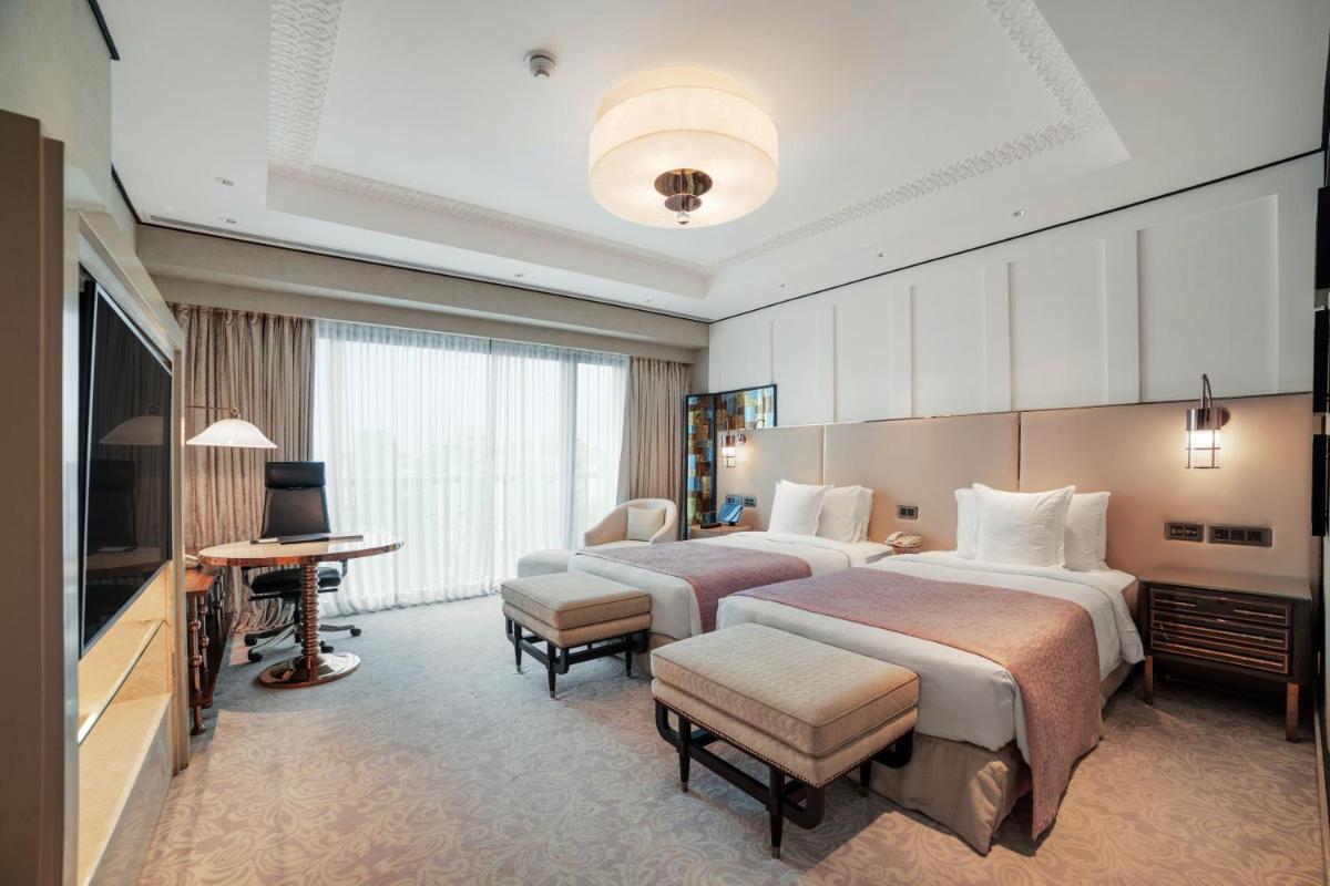 a hotel room with two beds and a television at ITC Narmada, a Luxury Collection Hotel, Ahmedabad in Ahmedabad
