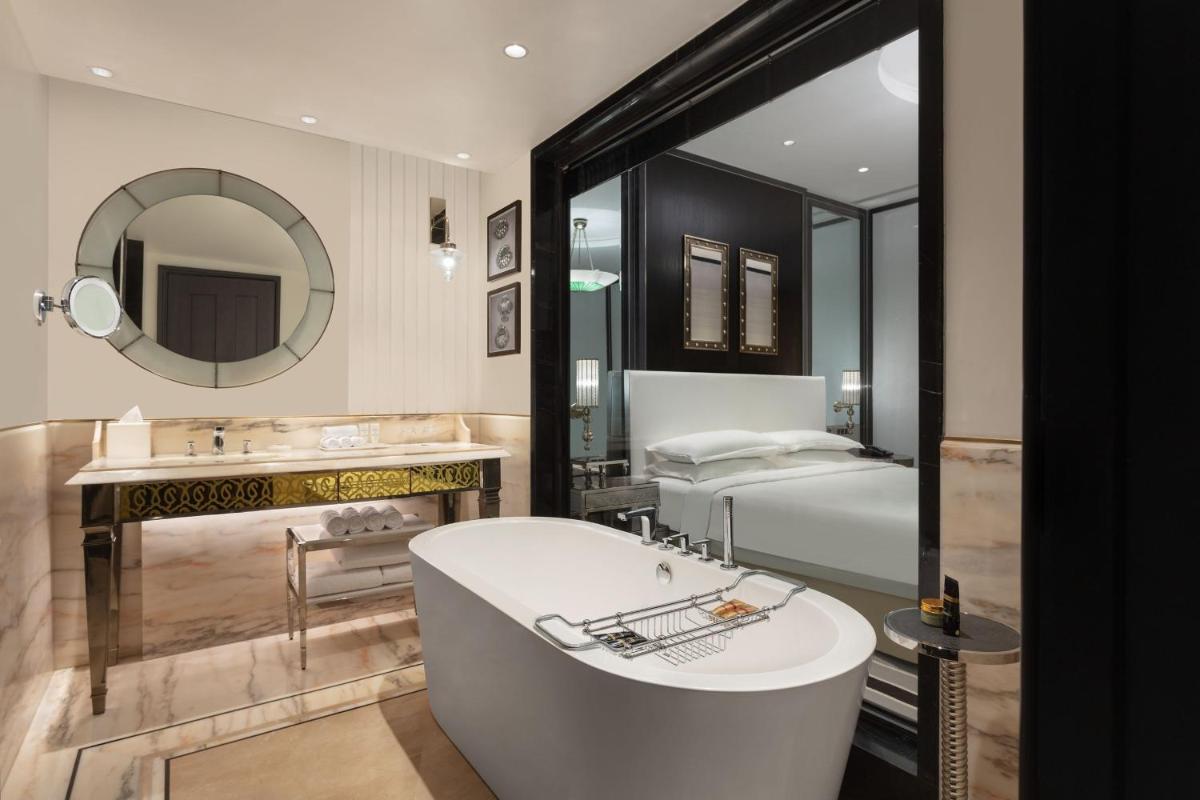 a bathroom with a tub and a bed and a mirror at ITC Narmada, a Luxury Collection Hotel, Ahmedabad in Ahmedabad