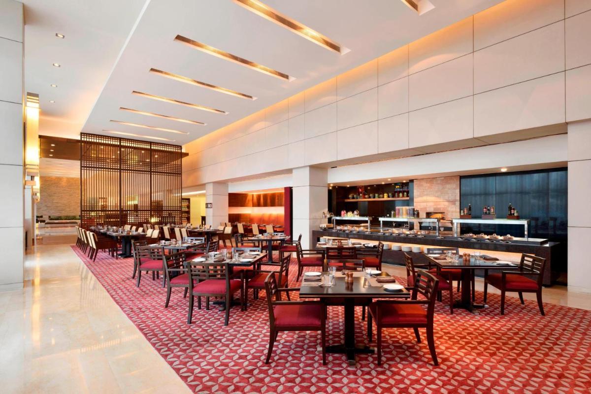 a restaurant with tables and chairs and a bar at Courtyard by Marriott Pune Hinjewadi in Pune
