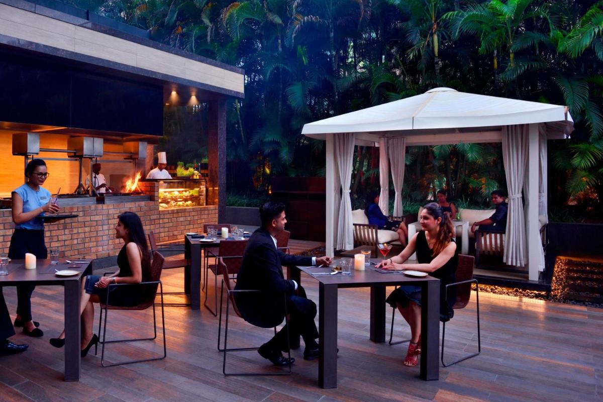 a group of people sitting at tables in a restaurant at Courtyard by Marriott Pune Hinjewadi in Pune