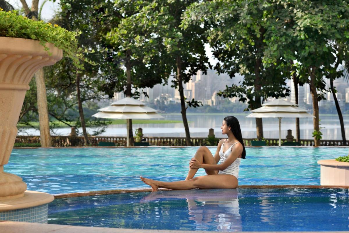a woman sitting on the edge of a swimming pool at The Westin Mumbai Powai Lake in Mumbai