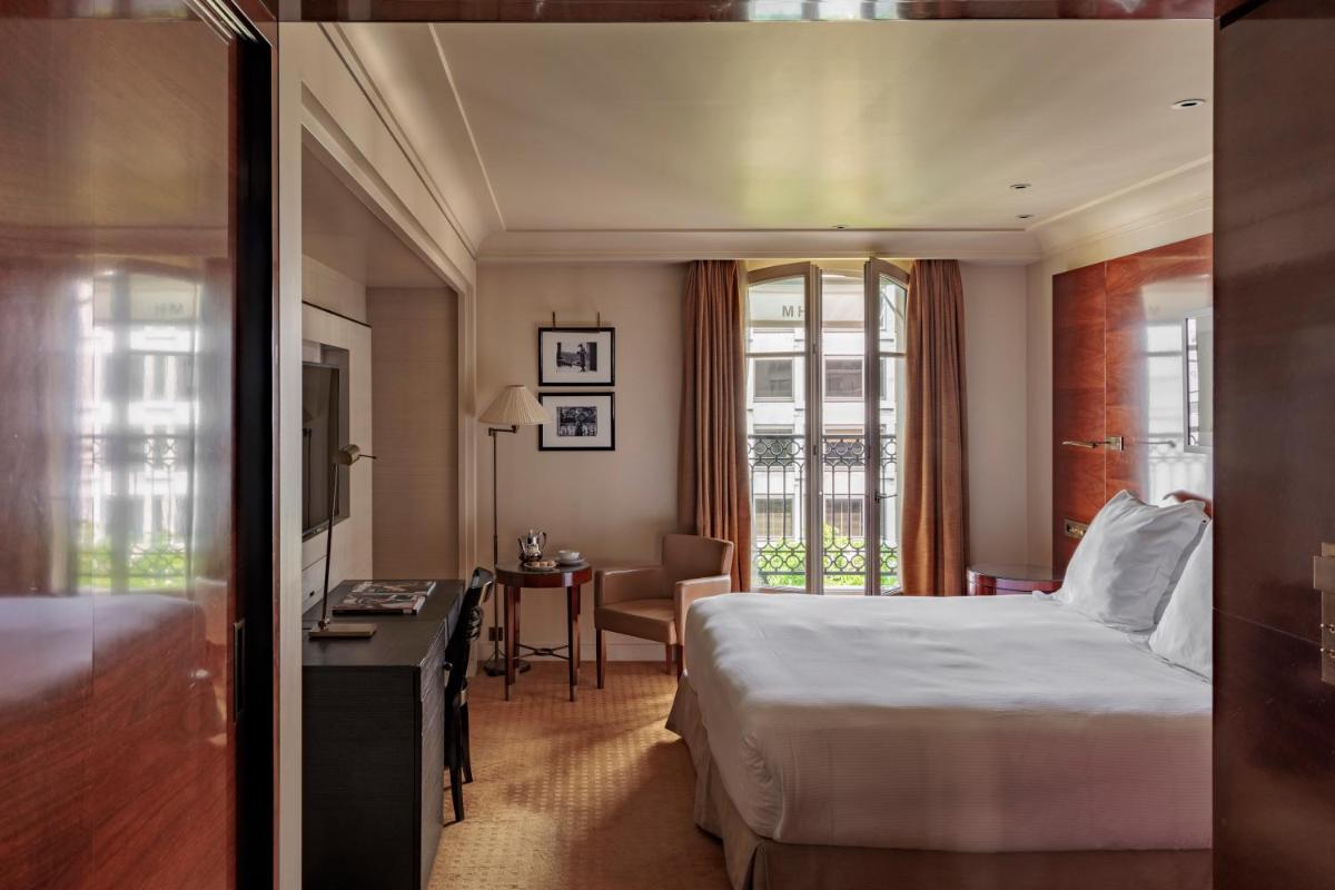 une chambre d'hôtel avec un lit et un bureau dans l'établissement Hotel Montaigne, à Paris