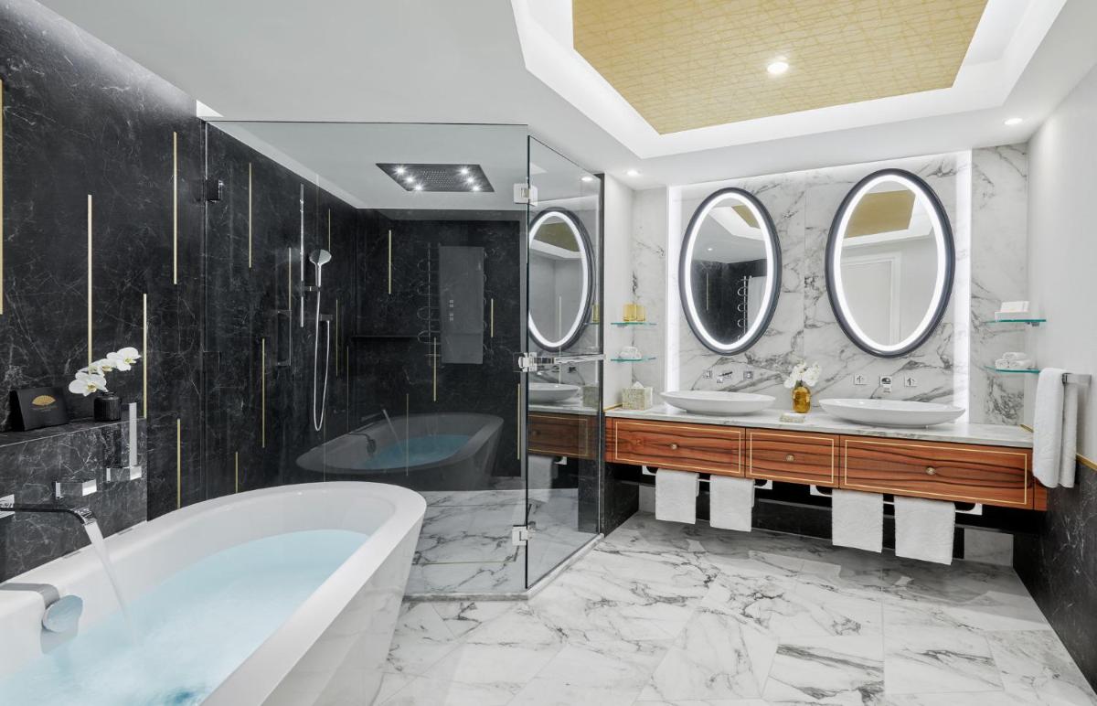 ein Badezimmer mit zwei Waschbecken und einer Badewanne und Spiegeln in der Unterkunft Mandarin Oriental, Munich in München