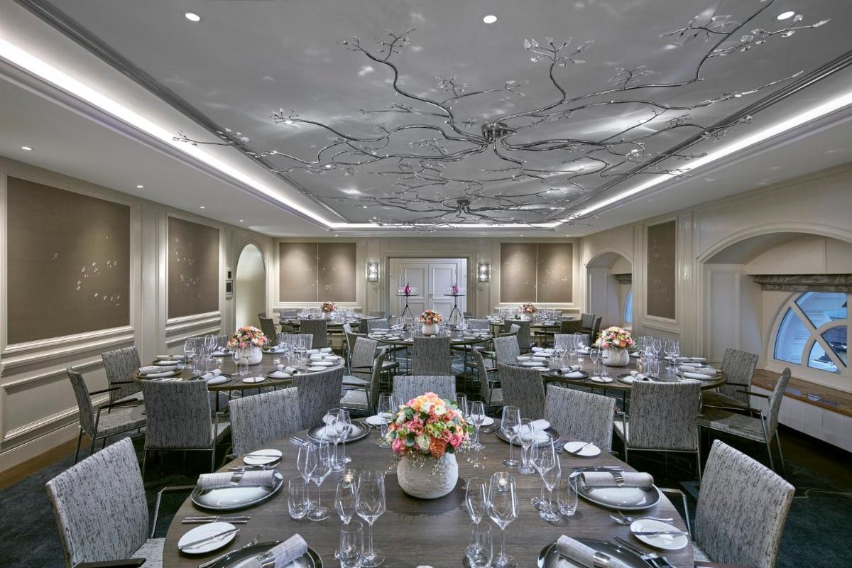 ein Bankettraum mit Tischen und Stühlen und einer Decke mit einem Baumbild in der Unterkunft Mandarin Oriental, Munich in München