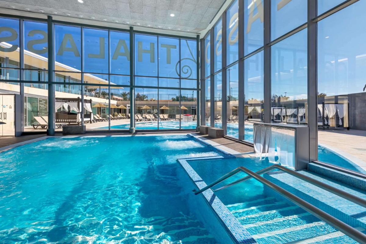 una piscina en un edificio con grandes ventanales en Barceló Fuerteventura Castillo, en Caleta de Fuste