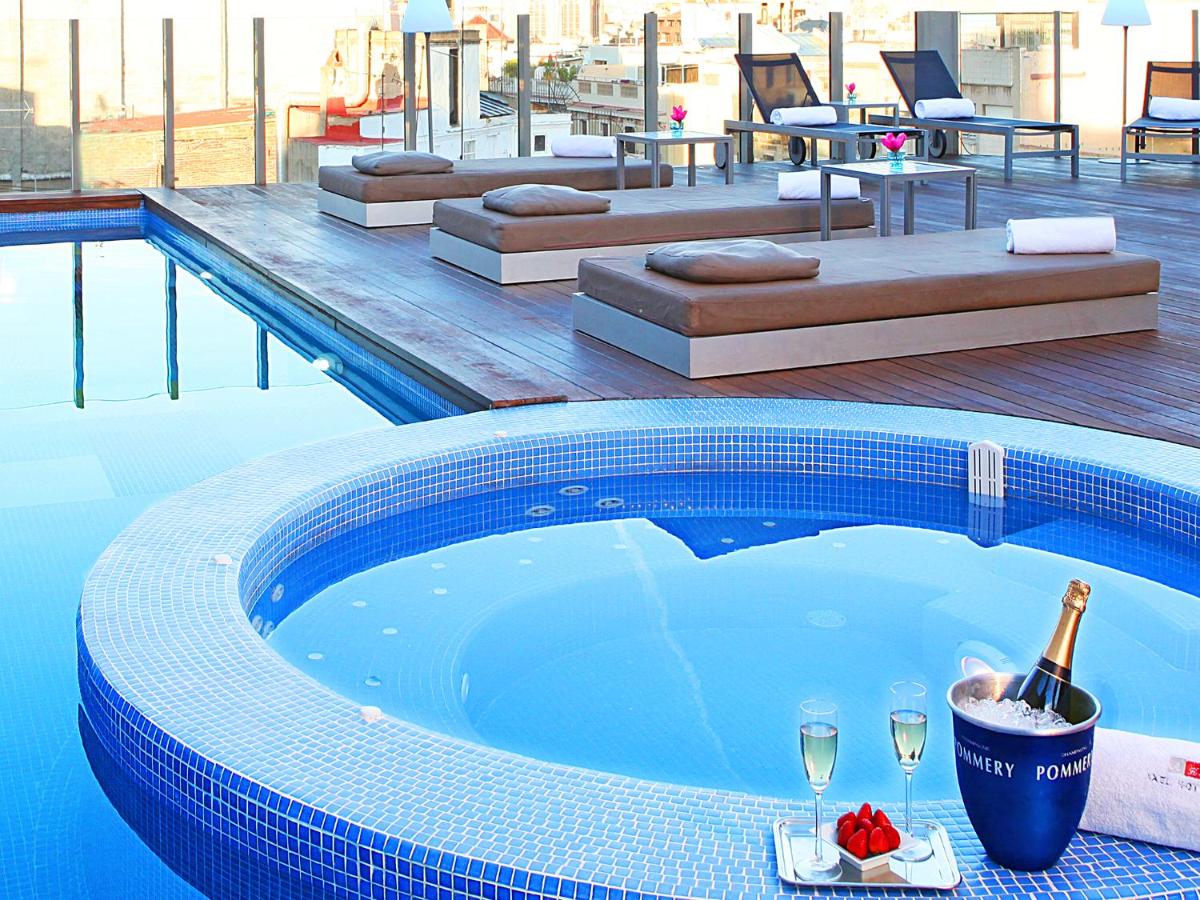 una piscina con una botella de champán y copas de vino en Axel Hotel Barcelona - Adults Only, en Barcelona